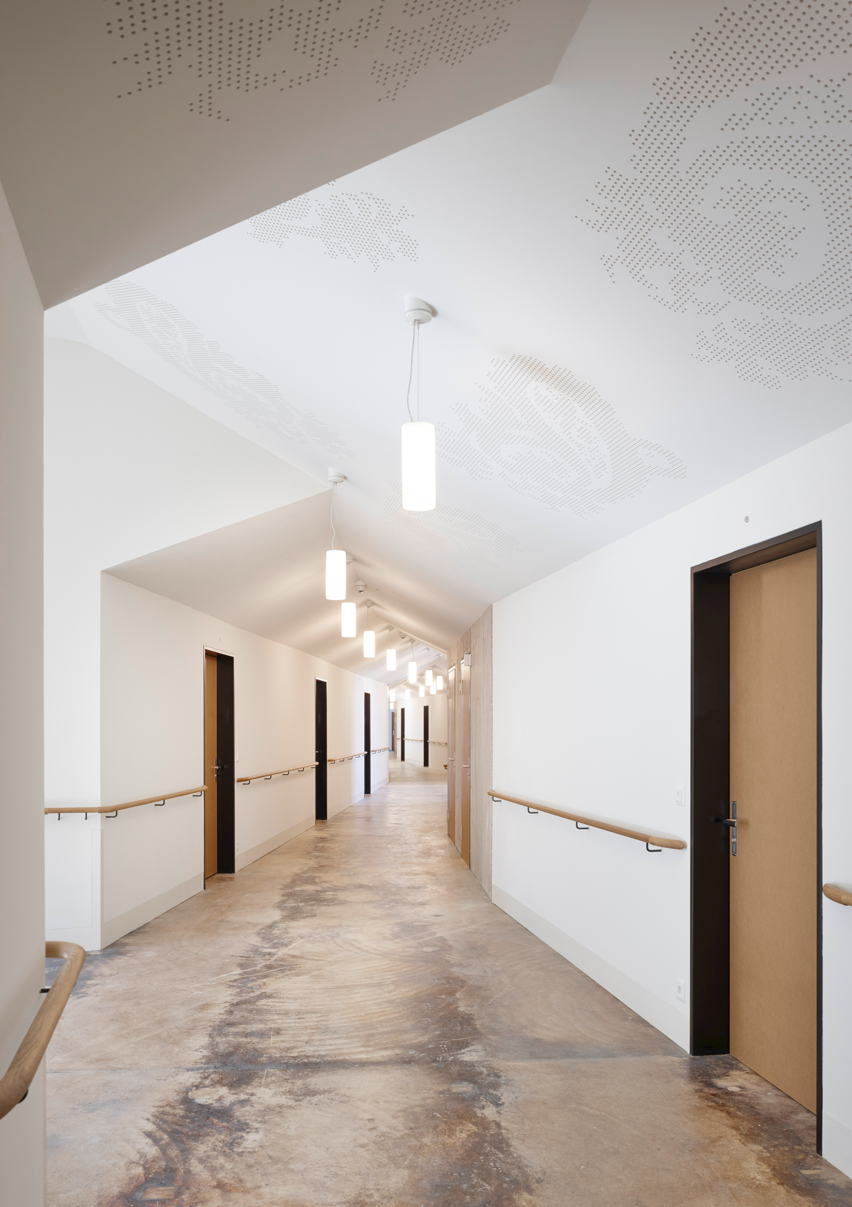 Zentrum Glarnersteg Schwanden, Korridor im umgebauten Bestandsgebäude mit erhaltenen Oberflächen der ehemaligen Textilfabrik.